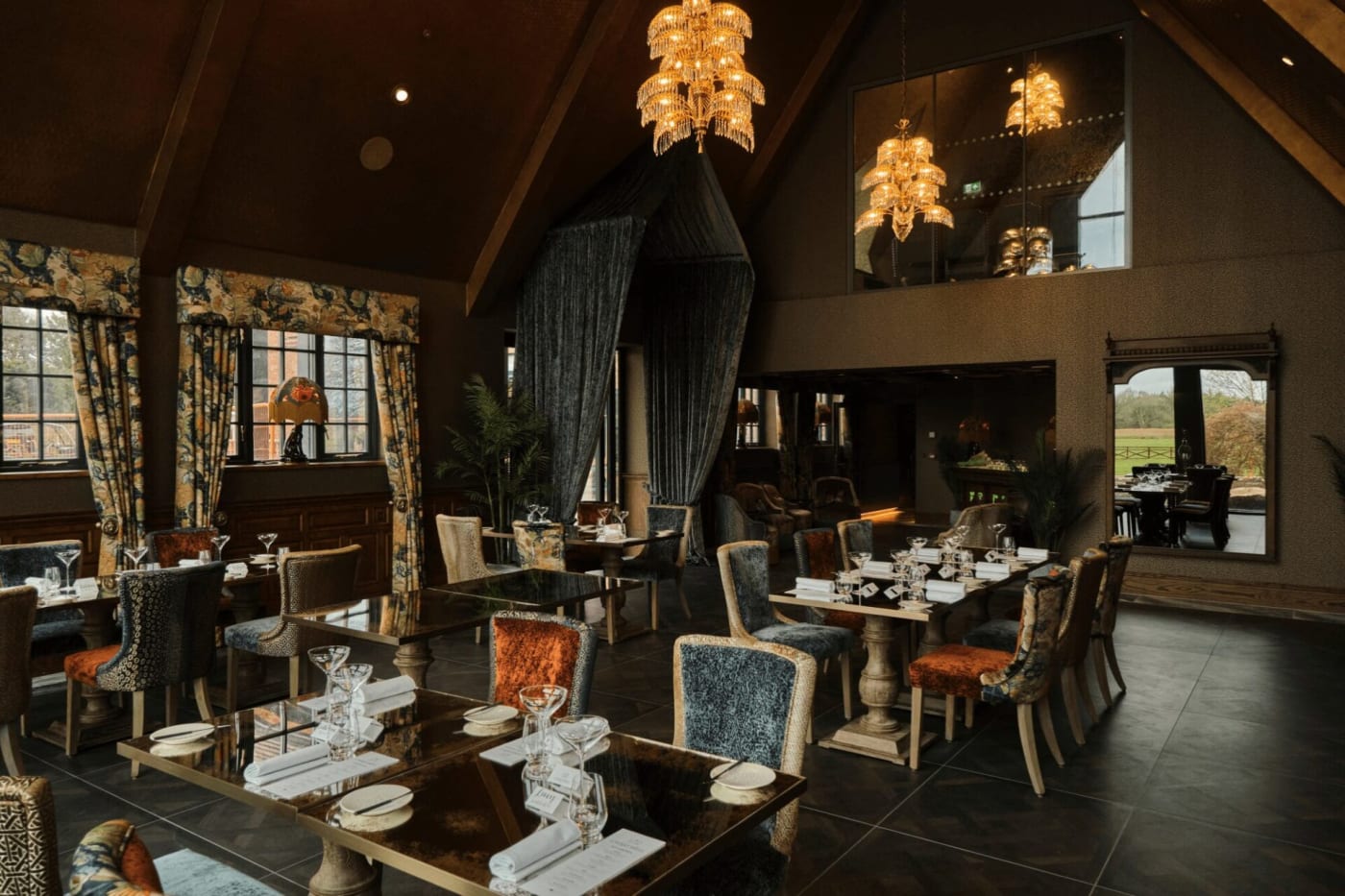 Salão do restaurante Chartwell do Aldwark Manor Estate sob vigas aparentes, com lustres e mezanino
