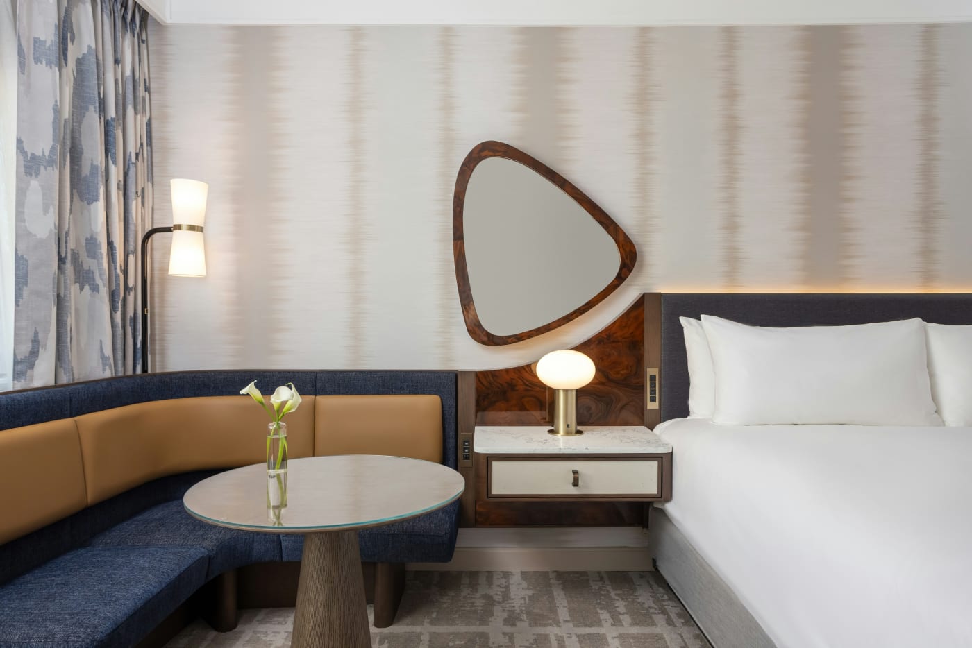 Um quarto renovado com cama king e banco estofado no Loews Nashville Hotel at Vanderbilt Plaza