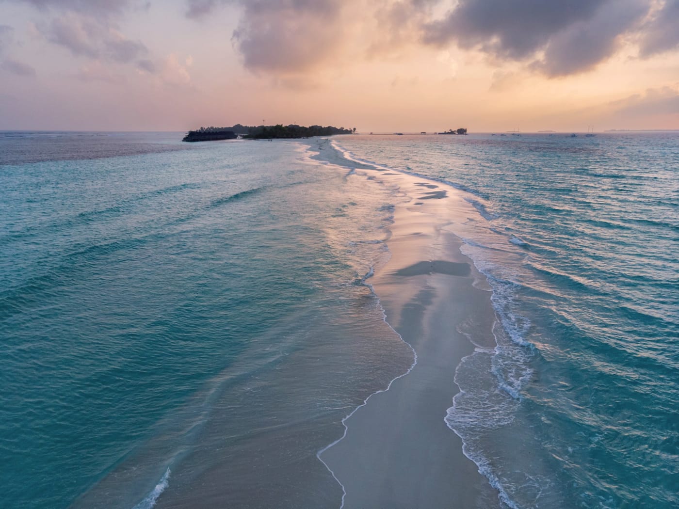 Un banc de sable blanc s'avance dans un lagon turquoise des Maldives au coucher du soleil, image officielle de Rosewood Ranfaru