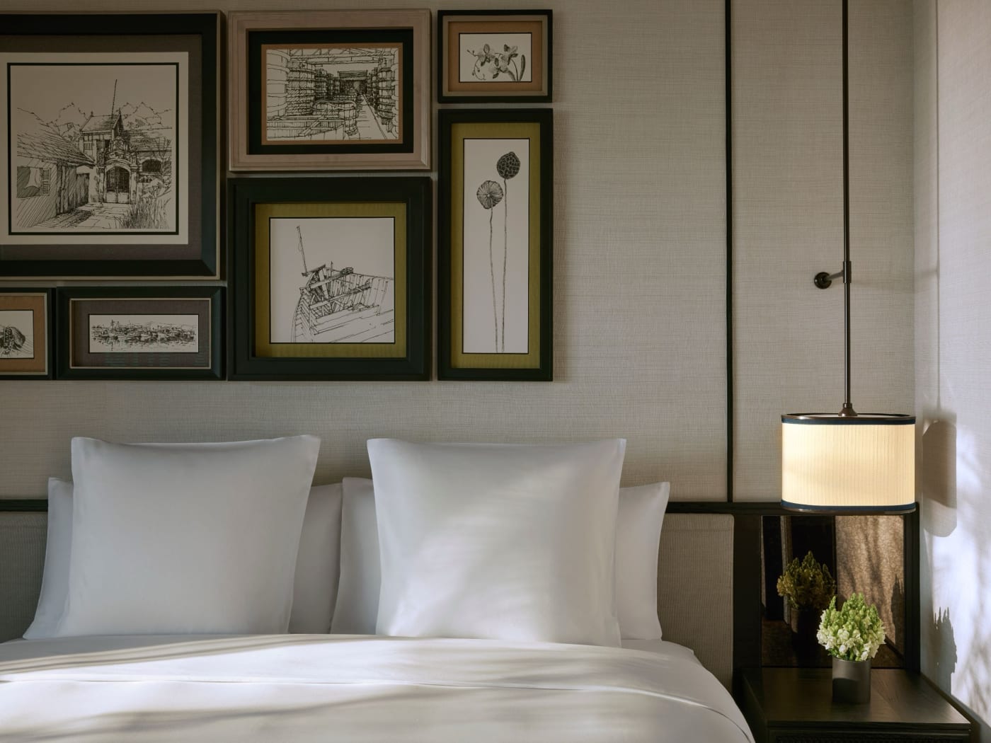 Lit d'une chambre front de mer du Park Hyatt Phu Quoc sous une série de dessins encadrés