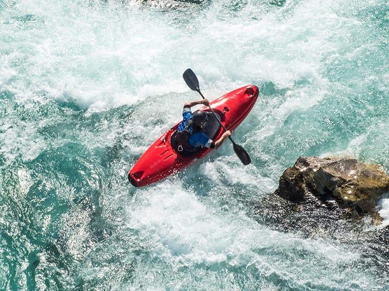 A kayaker paddling through white-water rapids