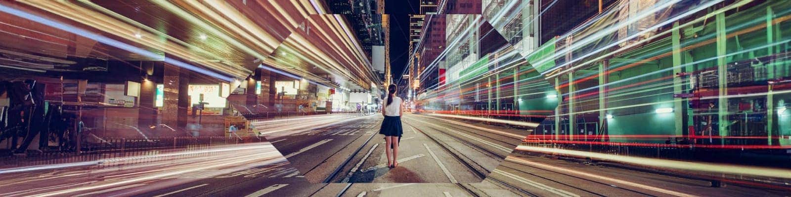 A woman standing amid the light trails of a city street at night