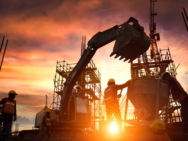 A construction site silhouetted against a sunset