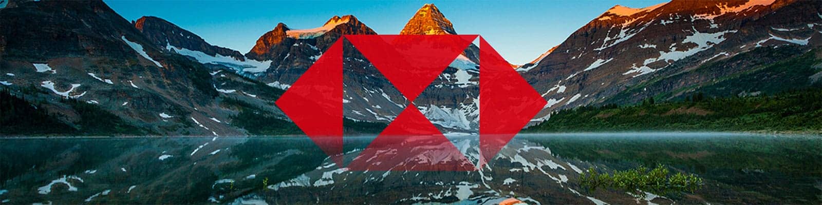 A mountain range reflected in a still lake at sunrise