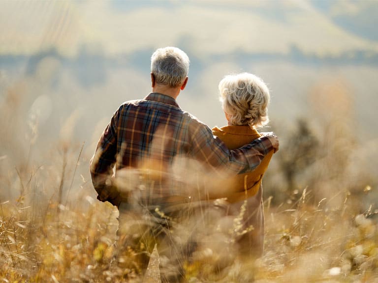 An older couple walking through a field