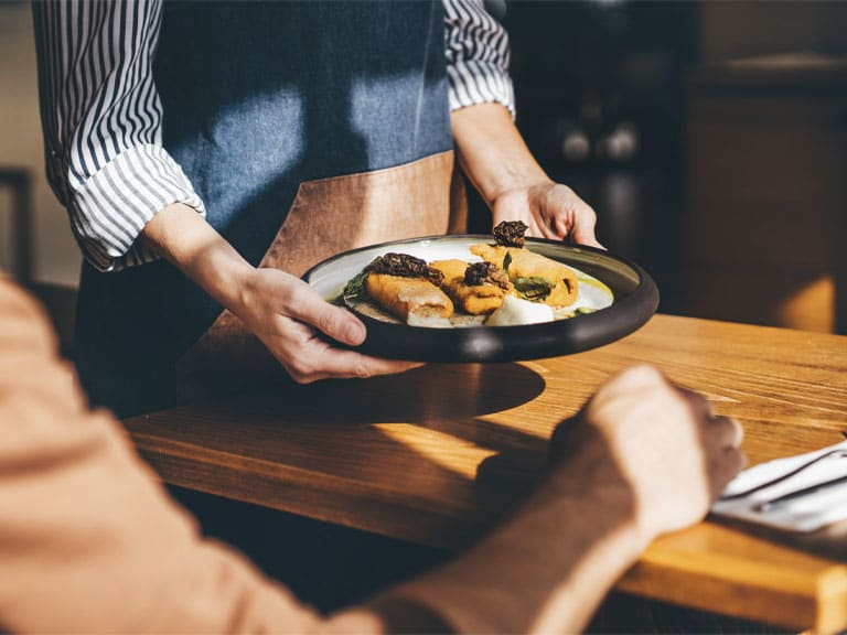 A waiter serving a plated meal