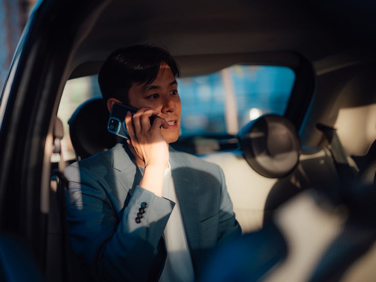 A businessman on the phone in the back of a car
