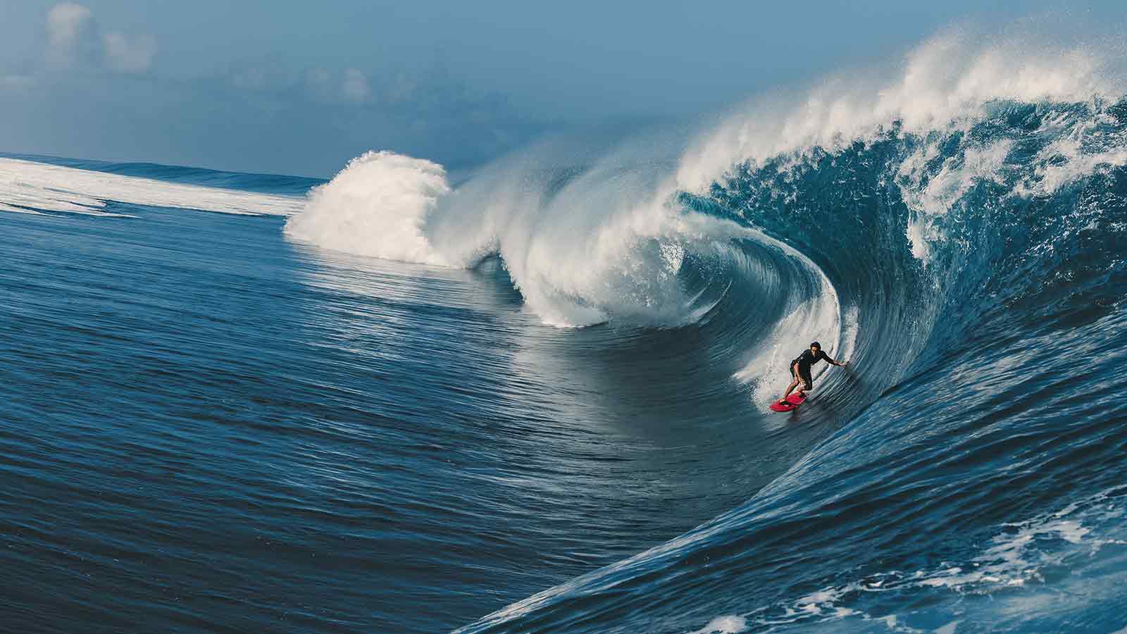 A surfer riding a wave at sunset