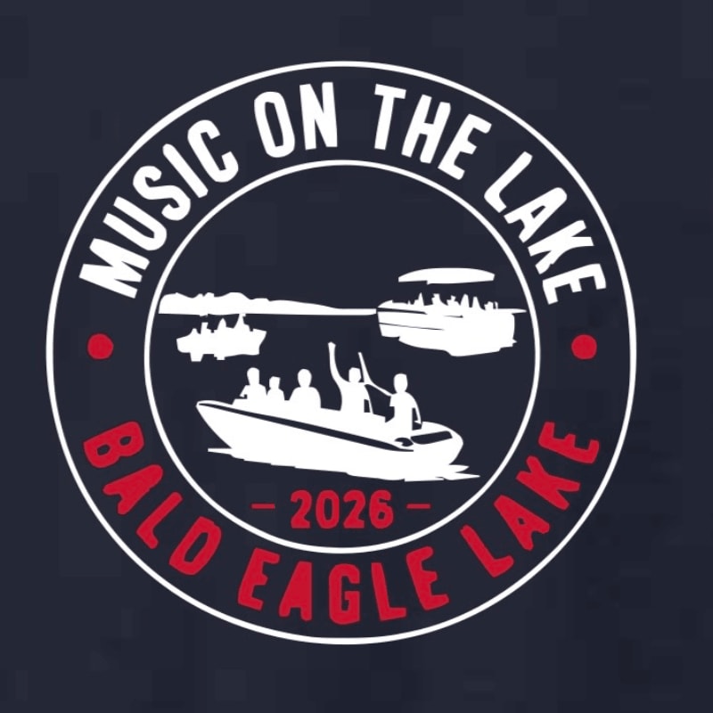 A circular logo with "MUSIC ON THE LAKE BALD EAGLE LAKE 2026" written around the edge, features a boat with people enjoying themselves in the foreground, and a distant shoreline with trees and other boats in the background.