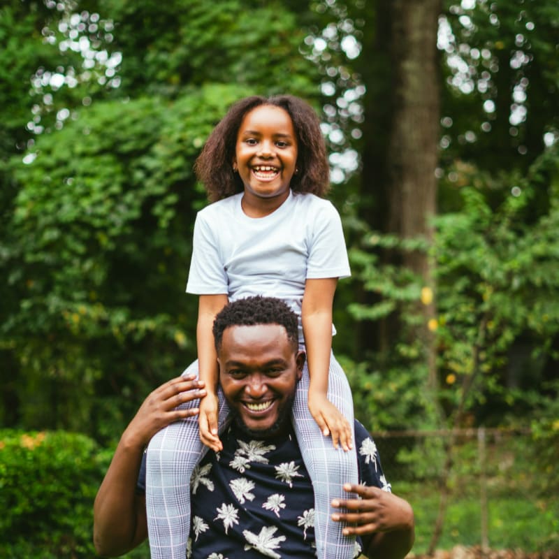 a man carrying a little girl on his shoulders