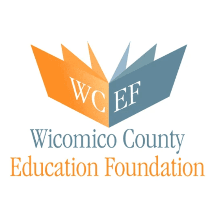 An open book with "WCEF" on its pages is set against a white background, with "Wicomico County Education Foundation" written below in blue and orange text.