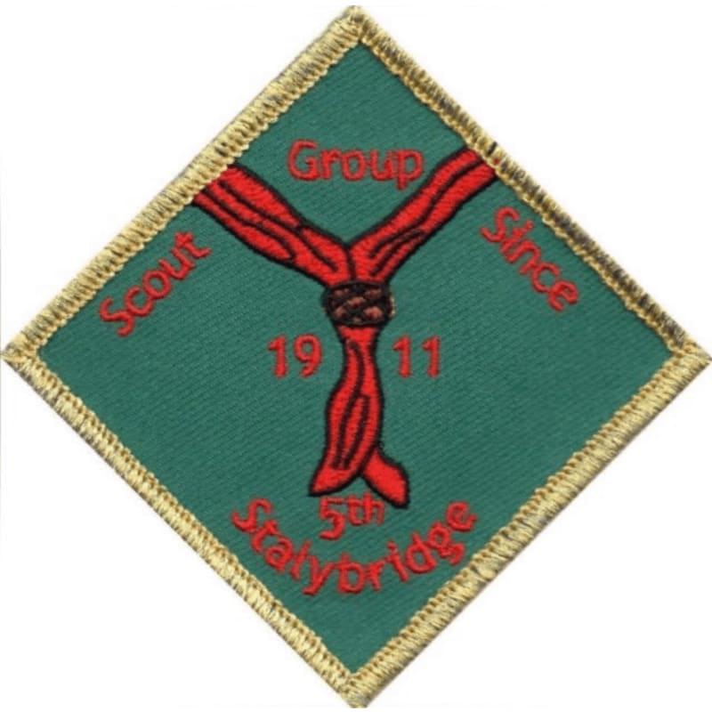 A diamond-shaped scout badge with a red knot and text on a green background is centered against a white backdrop.