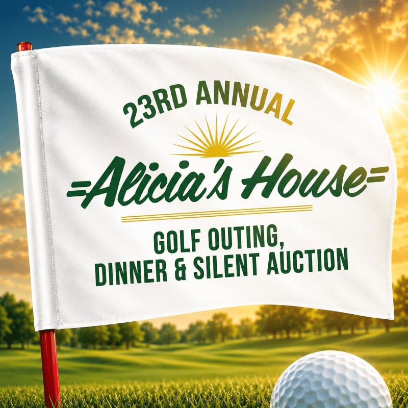 A white golf flag with event details stands in the foreground on a golf course, with a golf ball to its right, against a bright, sunny sky in the background.