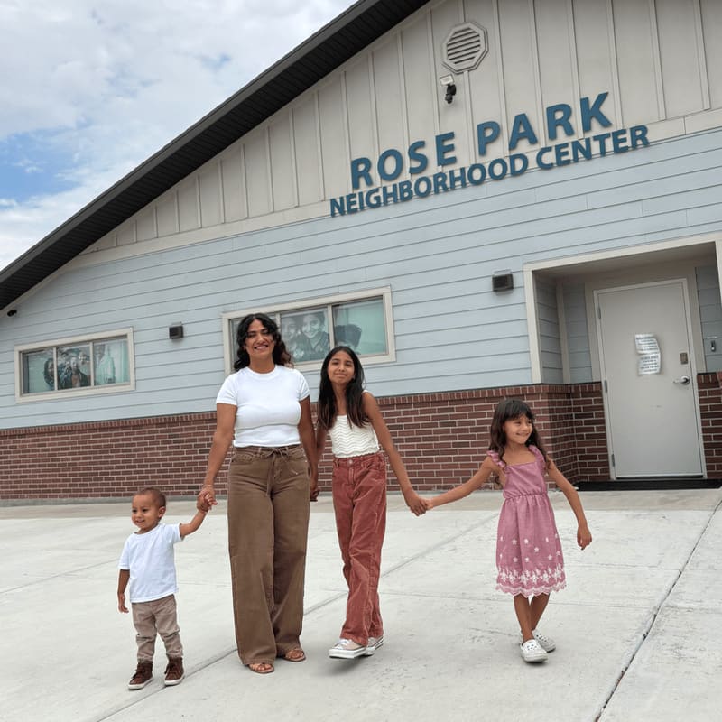 A woman and three children hold hands in front of the Rose Park Neighborhood Center.