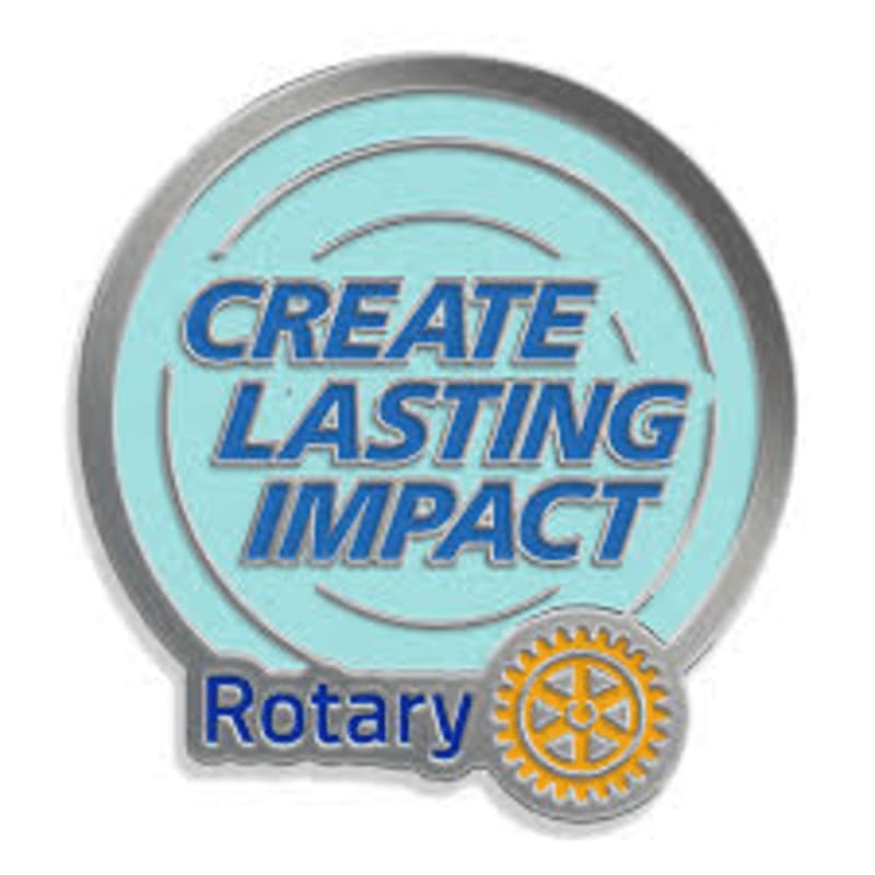 A circular emblem with the words "CREATE LASTING IMPACT" in blue lettering on a light blue background is in the foreground, with a smaller Rotary logo in the bottom right corner, all set against a white background.