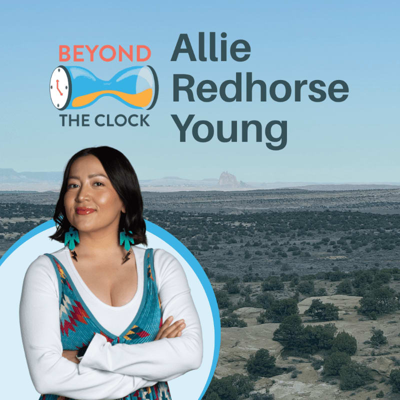 A woman with arms crossed in the foreground is superimposed over a vast, arid landscape with a distant mesa under a clear blue sky, with the text "BEYOND THE CLOCK Allie Redhorse Young" in the upper right.