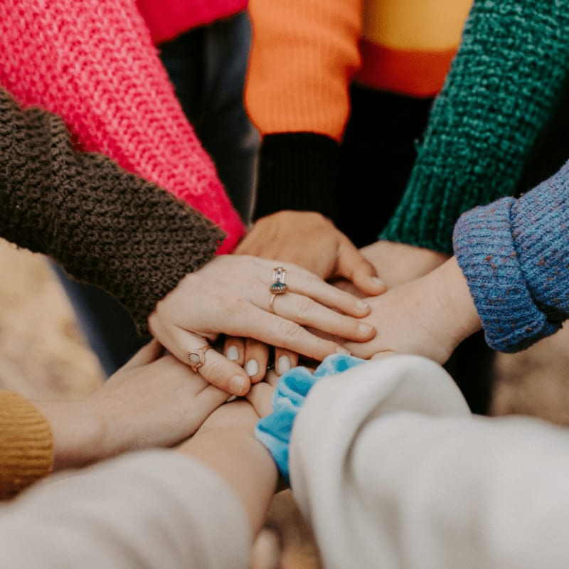 group stacking hands in colorful sweaters