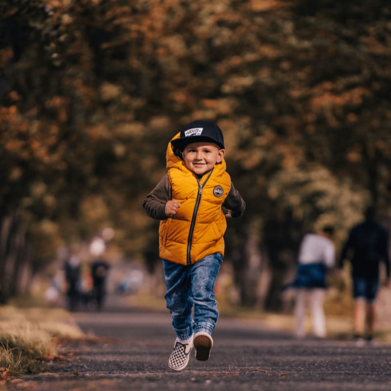 man in brown jacket and blue denim jeans walking on road during daytime
