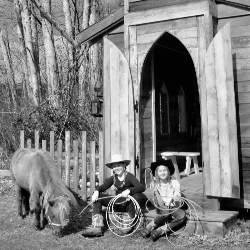 A sepia-toned image shows two figures in cowboy hats standing on a wooden porch in front of a rustic building with a "Cigar Lounge" sign, while trees are visible in the background.