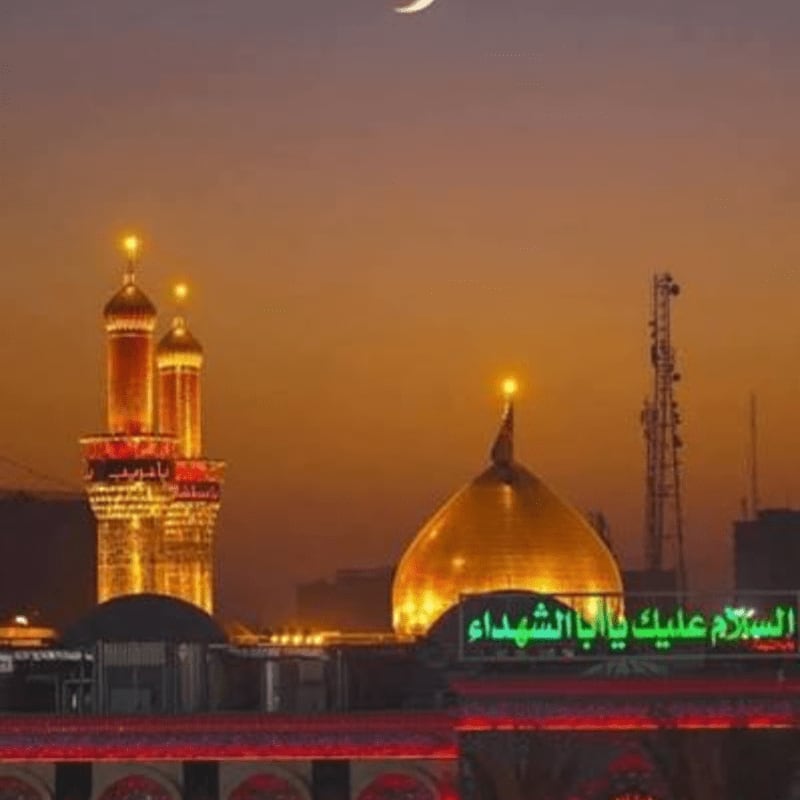Golden domes and minarets of a mosque are illuminated against an orange sky with a crescent moon, while a red-lit structure is visible in the foreground.
