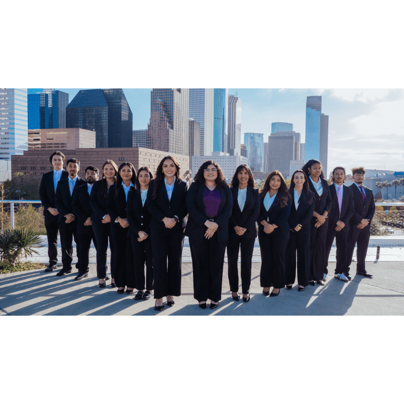 A group of professionals in suits stands in the foreground with a cityscape in the background.