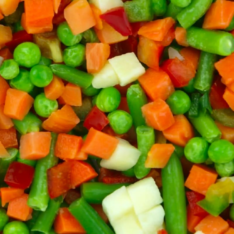 A close-up view of mixed vegetables, including bright green peas, orange carrots, and white potato chunks, fills the frame.