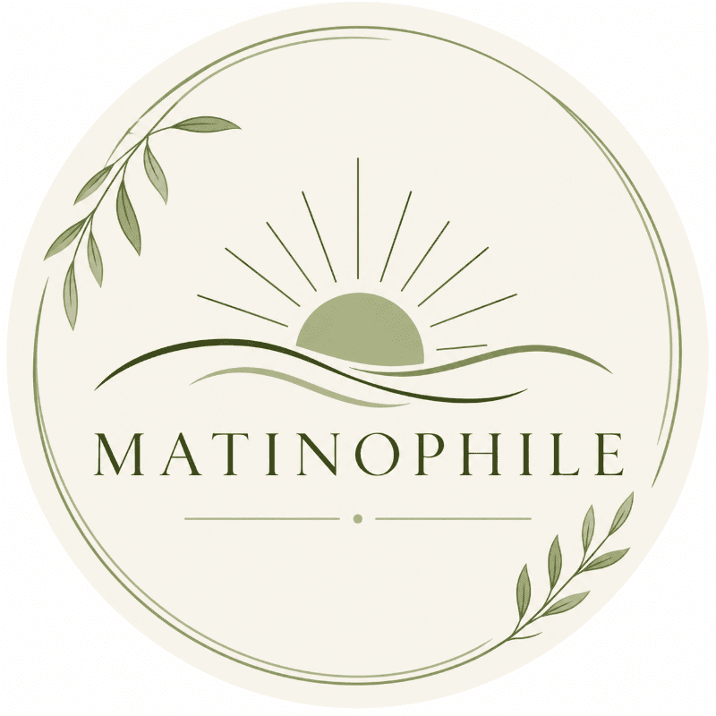 A circular logo with a sunrise over rolling hills in the center, the word "MATINOPHILE" below it, and leafy branches framing the top and bottom edges.