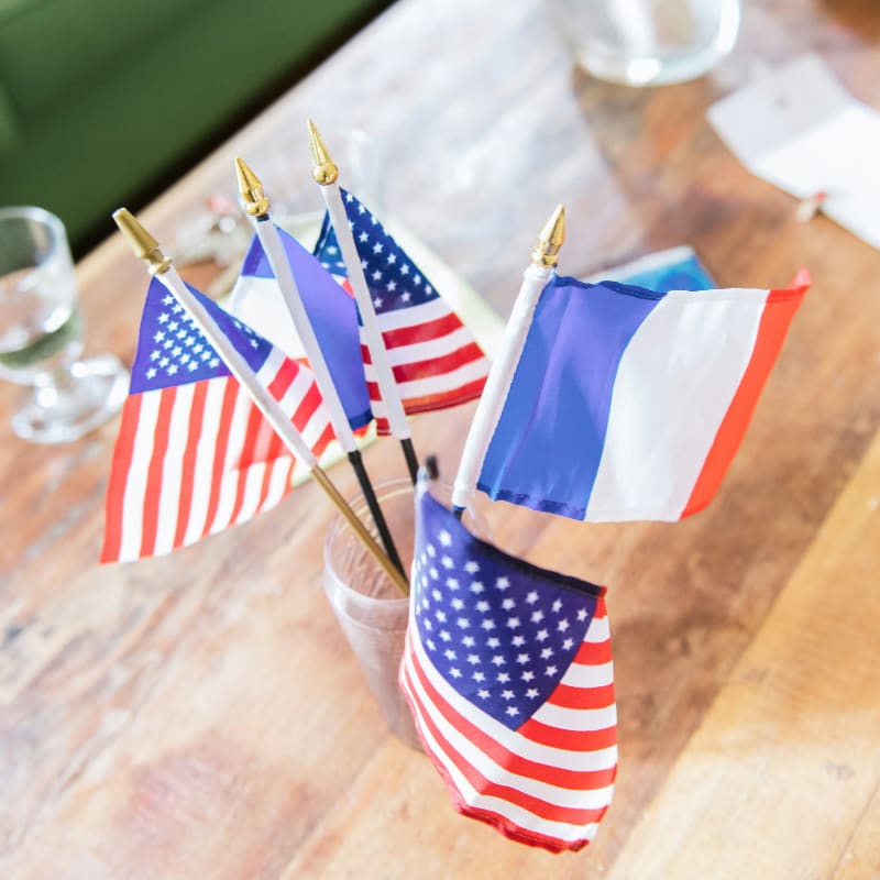 a wooden table topped with american and french flags