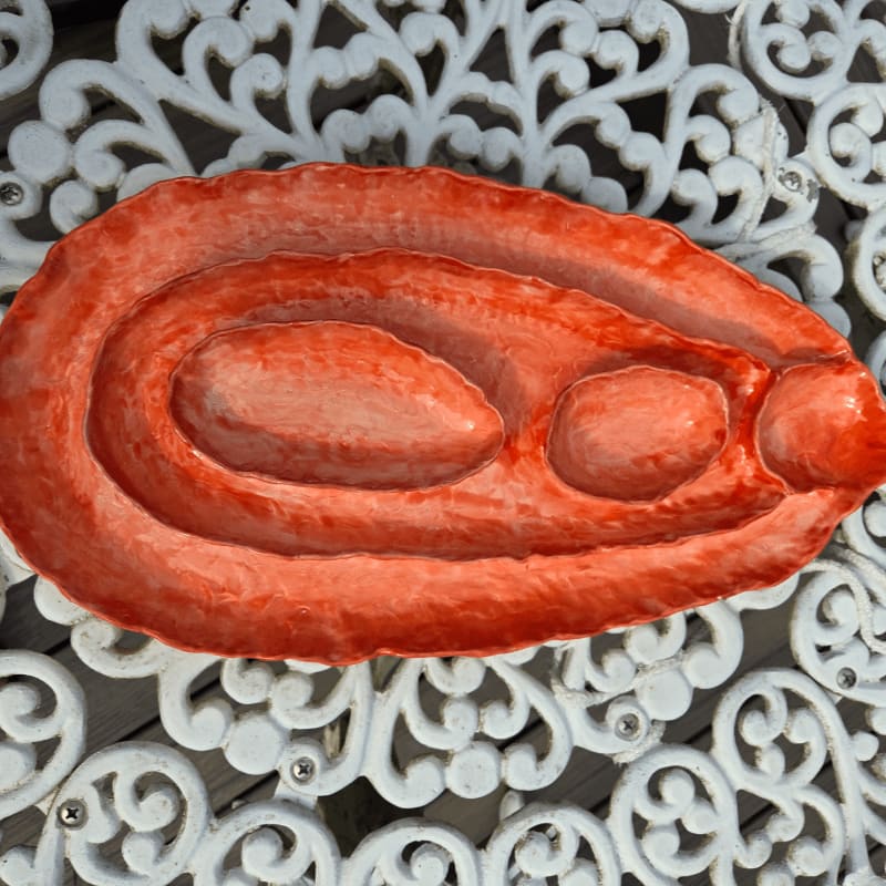A textured, orange, oval-shaped object rests on a white, ornate metal surface.