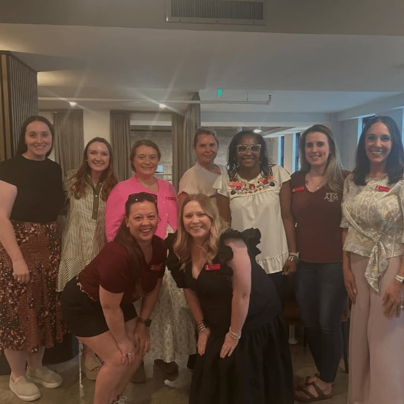 A group of women pose for a photo in a well-lit room with modern decor.