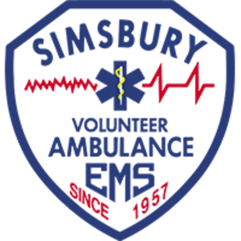 A blue and white shield with "SIMSBURY VOLUNTEER AMBULANCE EMS SINCE 1957" written inside, featuring a red electrocardiogram line and a blue Star of Life emblem, is set against a plain white background.