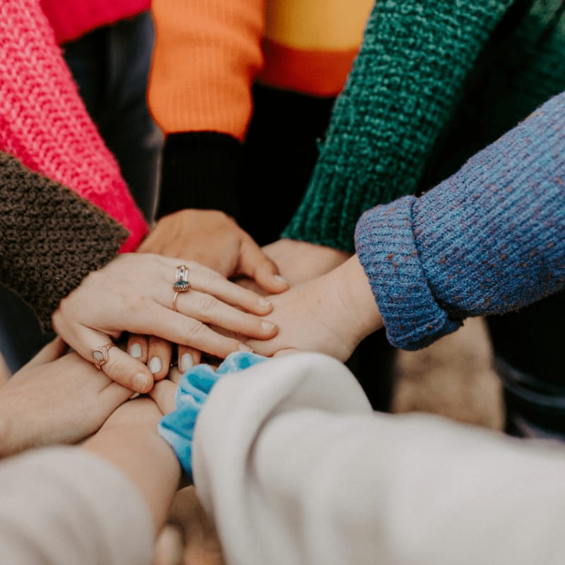 group stacking hands in colorful sweaters