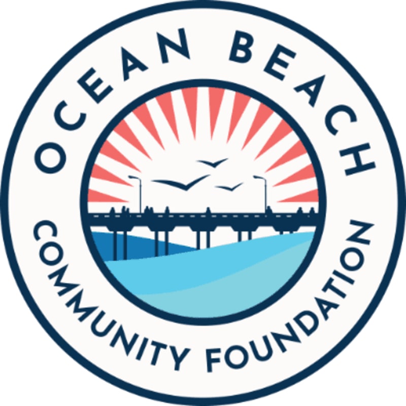 A circular logo features a stylized pier and seagulls over water in the foreground, with a sunburst and the words "OCEAN BEACH COMMUNITY FOUNDATION" in the background.