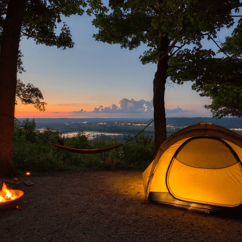 a tent set up in the woods at sunset