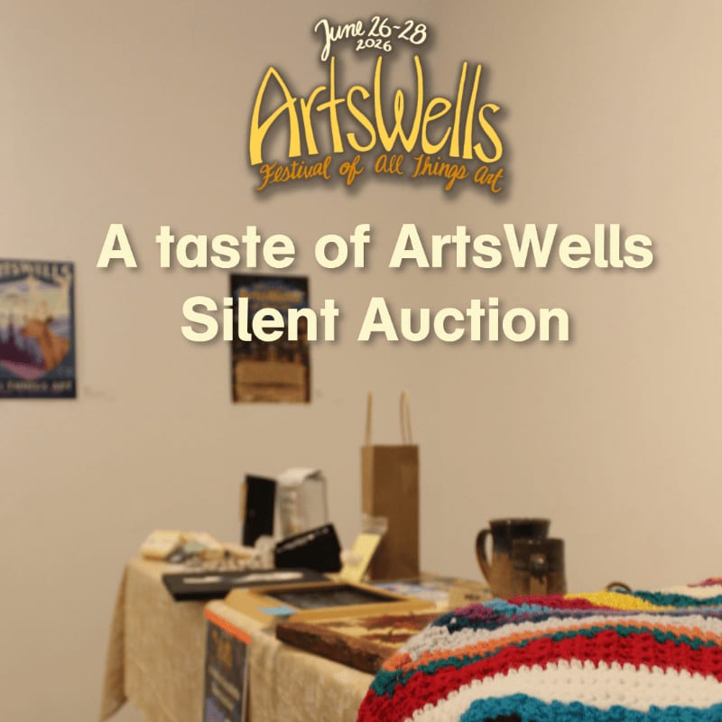 A table laden with items for a silent auction sits in the foreground, with a poster and a blank wall in the background.