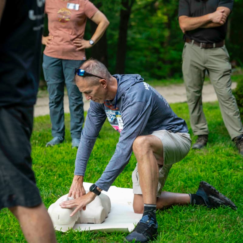 Man practices cpr on a dummy with others watching