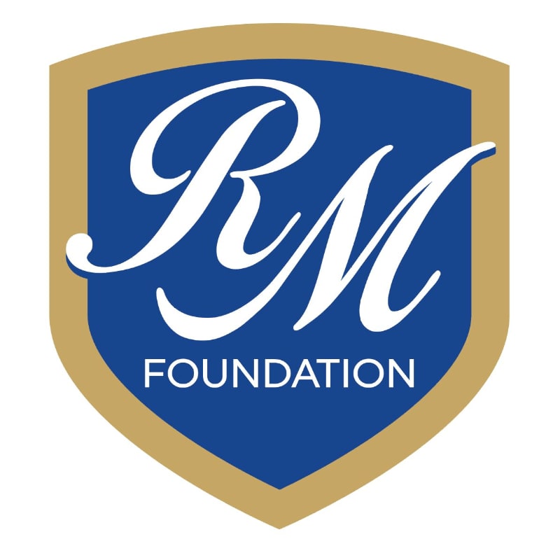 A blue shield with a gold border contains the white cursive letters "RM" above the word "FOUNDATION" in white block letters.