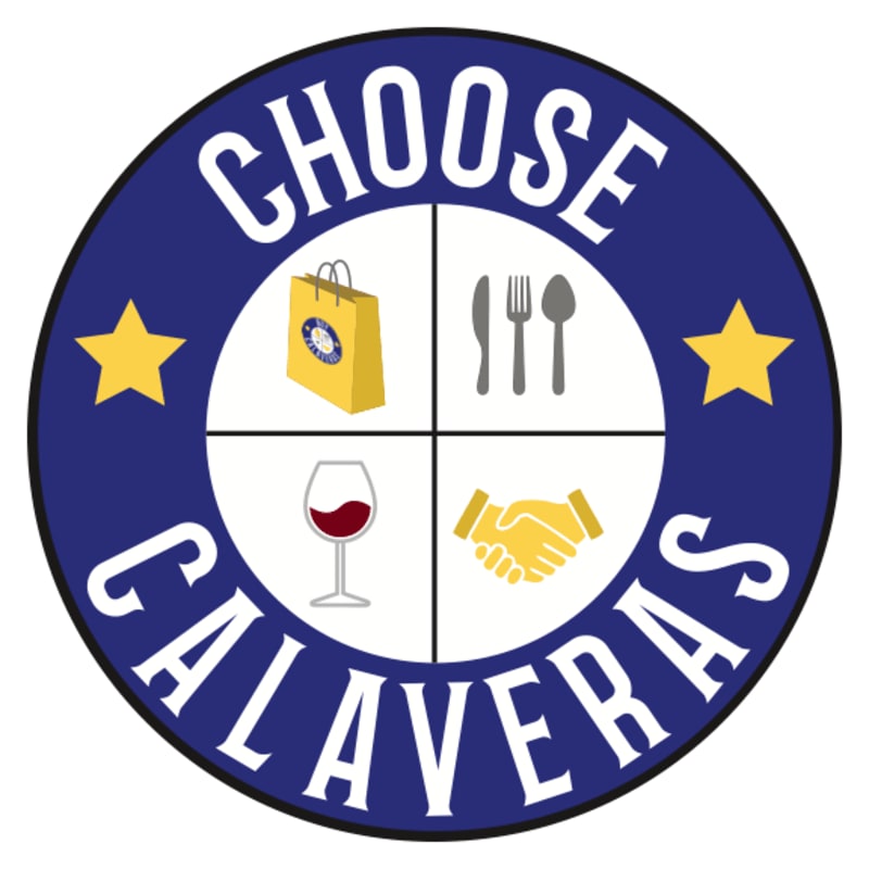 A circular logo with "CHOOSE CALAVERAS" written around the edge, featuring four quadrants with icons of a shopping bag, cutlery, a wine glass, and shaking hands, set against a blue and white background with yellow stars.