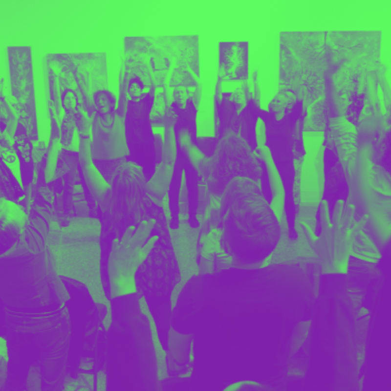 A group of people with their arms raised in a room with artwork on the walls.