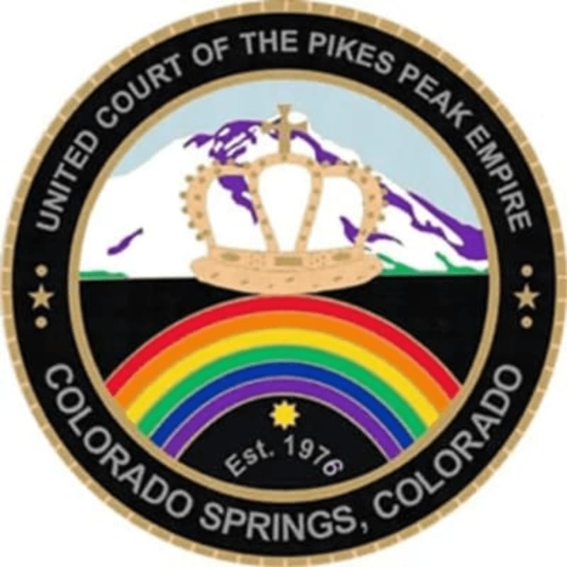 A crown sits atop a rainbow in the foreground, with a snow-capped mountain range in the background, all within a circular emblem.