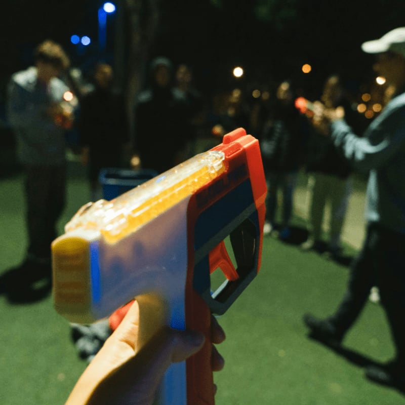People play a game with toy guns at night.