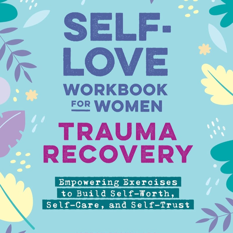 A pastel blue background with floral accents frames the title "SELF-LOVE WORKBOOK FOR WOMEN TRAUMA RECOVERY" in bold purple and pink lettering, with a subtitle about empowering exercises below.
