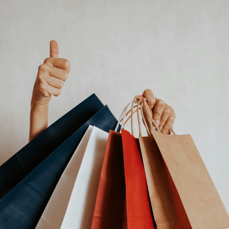 Person holding shopping bags with a thumbs up