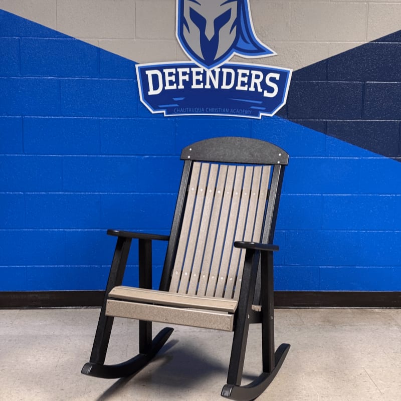 A weathered rocking chair sits in front of a blue and gray wall with a "Defenders" logo.