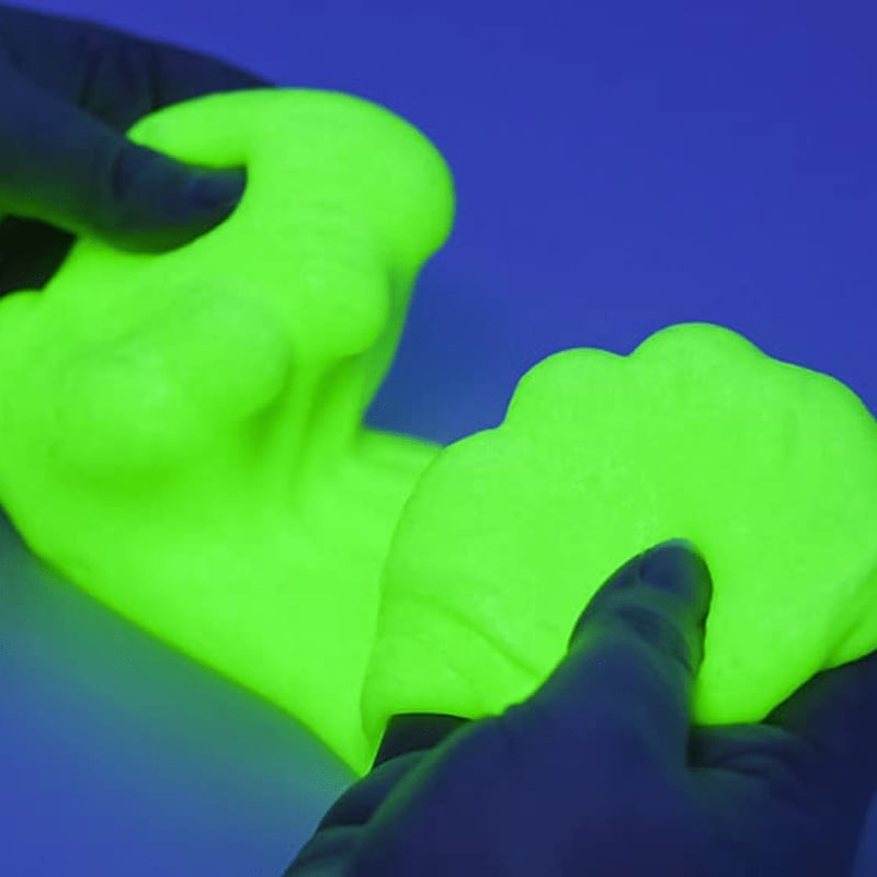 Hands mold glowing neon green slime against a dark blue background.
