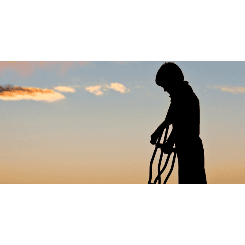 A silhouetted child stands in the foreground holding a rope against a backdrop of a soft, gradient sky with wispy clouds.