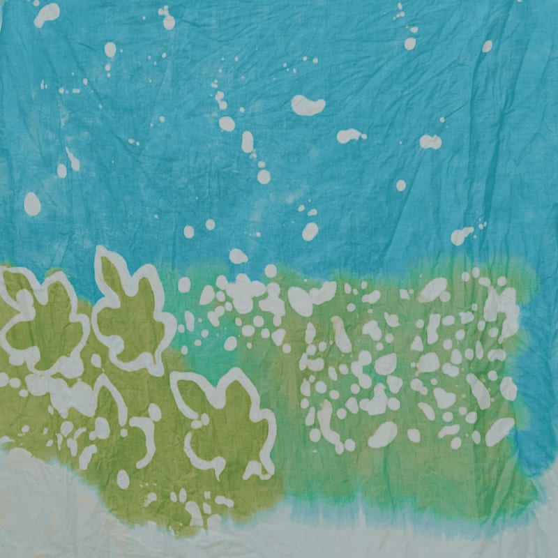 White floral shapes and splatters are set against a textured background of blue and green dye.