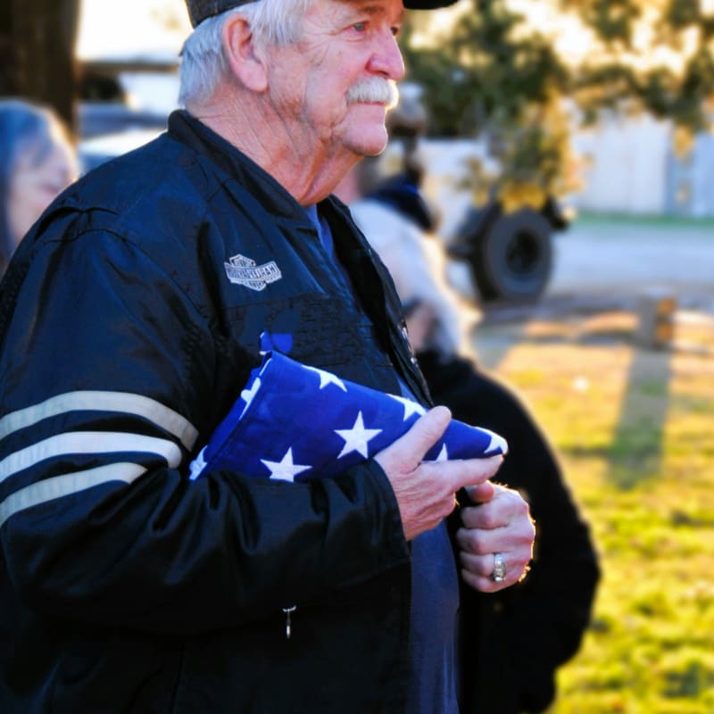 A man in a black jacket holding an american flag