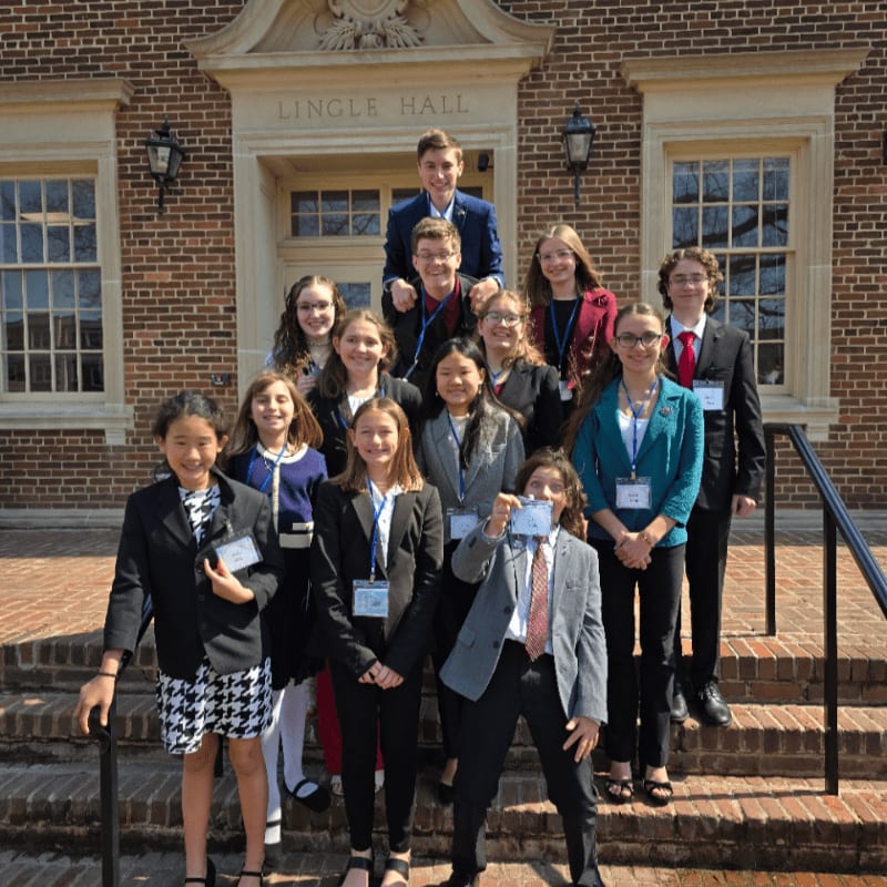 A group of formally dressed students poses on the steps of a brick building with "Lingle Hall" inscribed above the entrance.