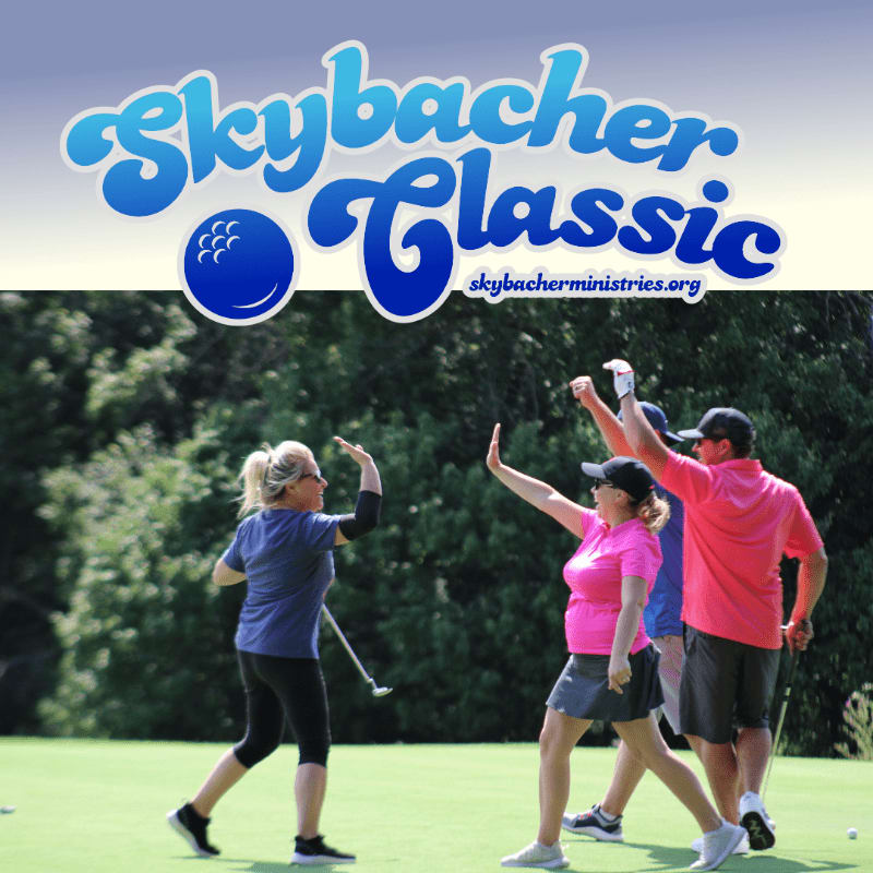Four golfers celebrate on a green with trees and a blue sky in the background, under a "Skybacher Classic" logo.